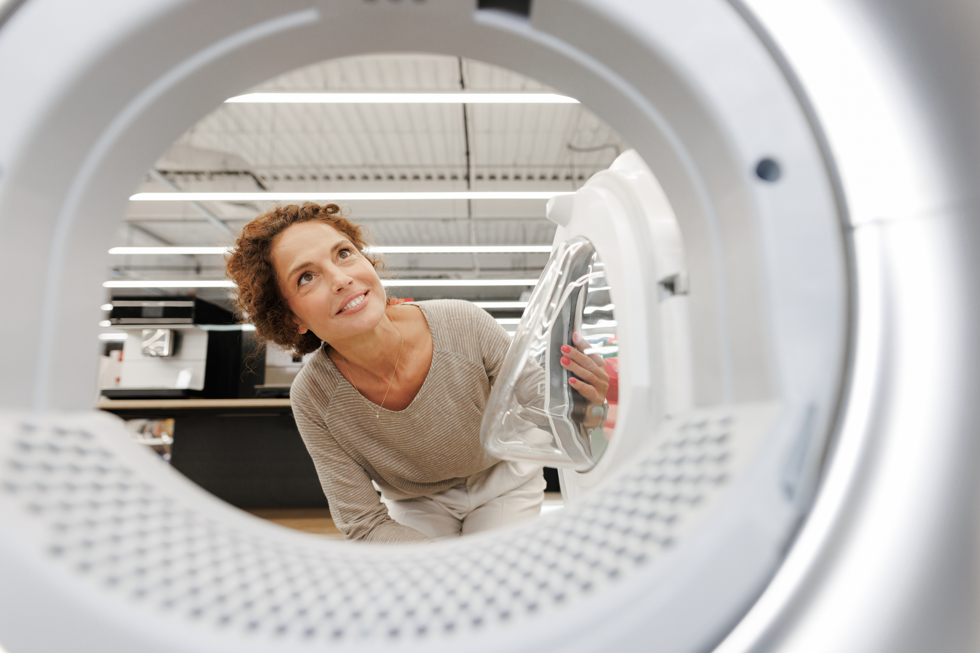 POV of a smiling woman looking into a front load washer